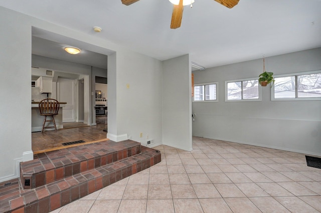 tiled spare room featuring ceiling fan and a healthy amount of sunlight