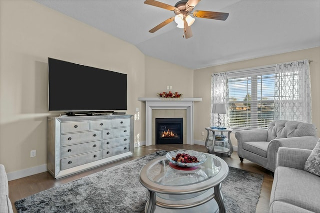 living room featuring wood-type flooring, ceiling fan, lofted ceiling, and a tiled fireplace