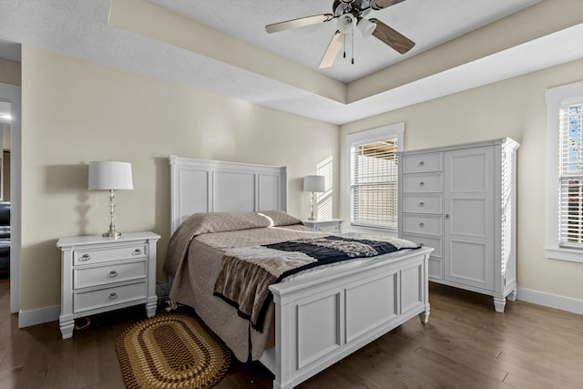 bedroom featuring multiple windows, ceiling fan, dark wood-type flooring, and a textured ceiling