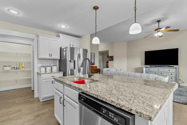 kitchen with white cabinets, hanging light fixtures, an island with sink, appliances with stainless steel finishes, and light hardwood / wood-style floors