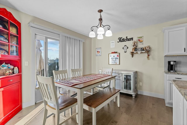 dining space with hardwood / wood-style floors and an inviting chandelier