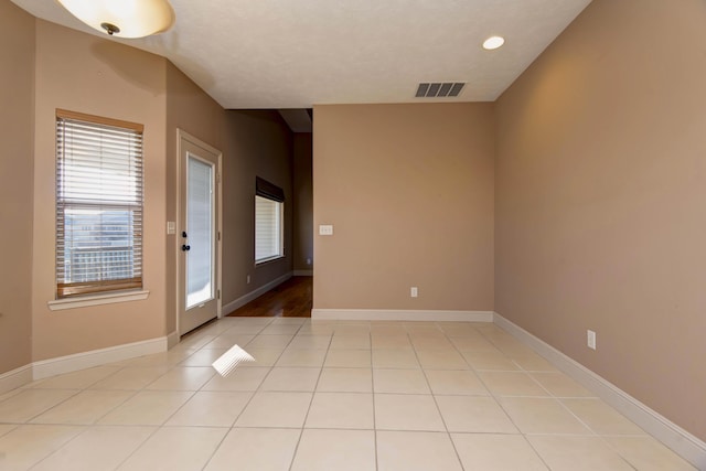 tiled spare room featuring a textured ceiling