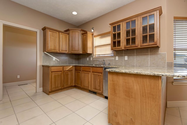 kitchen featuring sink, light stone counters, backsplash, kitchen peninsula, and light tile patterned flooring