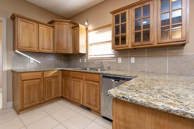 kitchen featuring dishwasher, decorative backsplash, light stone counters, and sink