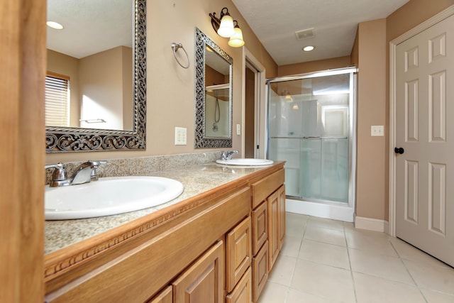 bathroom with a shower with door, vanity, and tile patterned flooring