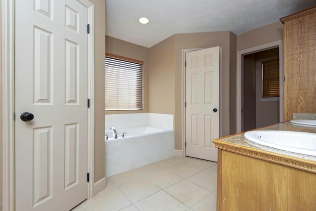 bathroom featuring tile patterned floors, vanity, a tub to relax in, and a textured ceiling