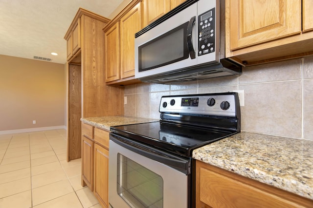 kitchen featuring light stone countertops, light tile patterned floors, backsplash, and stainless steel appliances