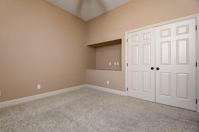 unfurnished bedroom with light colored carpet and a closet