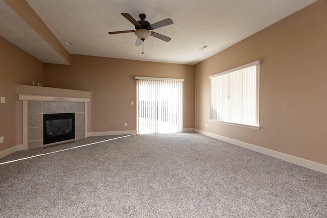 unfurnished living room featuring ceiling fan, carpet floors, and a tiled fireplace