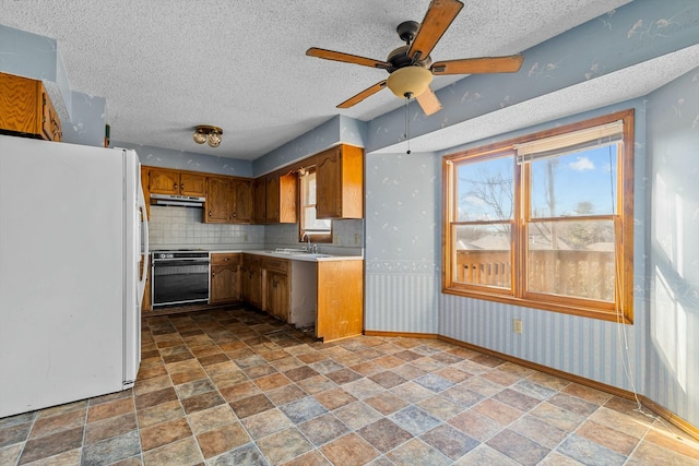 kitchen with white refrigerator, black stove, ceiling fan, decorative backsplash, and a textured ceiling