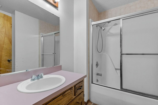 bathroom with shower / bath combination with glass door, vanity, and a textured ceiling