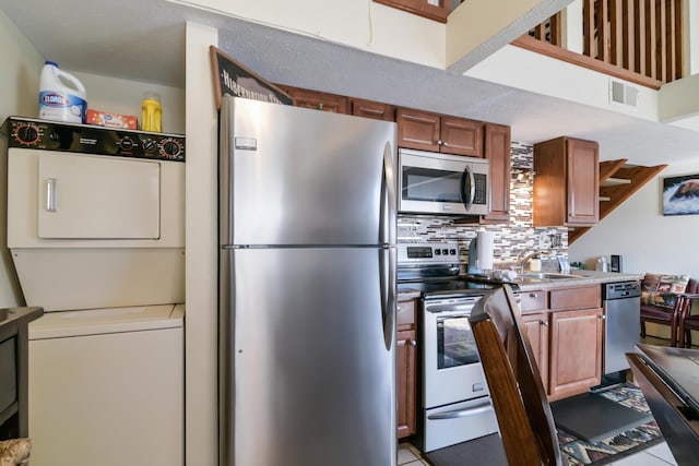 14 Scenic Ct Unit 8, Branson, MO 65616 - kitchen with stacked washer and dryer, a sink, tasteful backsplash, brown cabinets, and appliances with stainless steel finishes