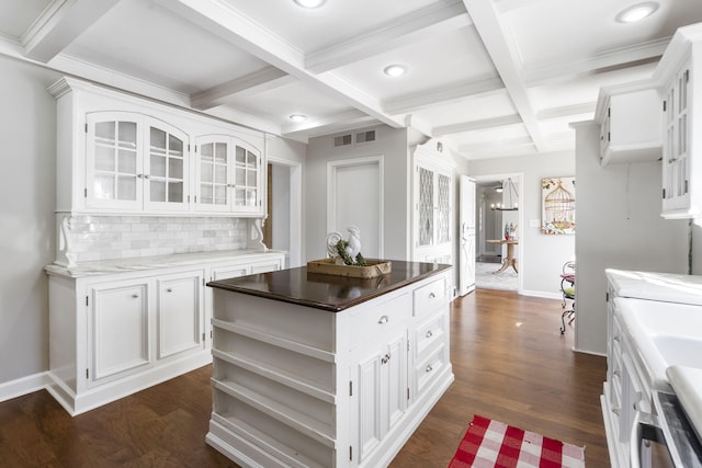 kitchen with tasteful backsplash, coffered ceiling, dark wood-type flooring, white cabinets, and a kitchen island