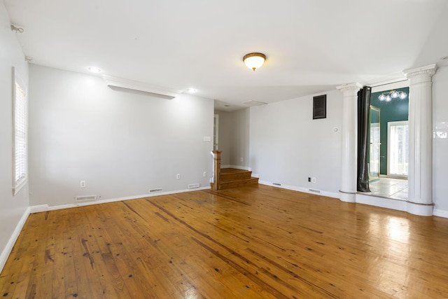 unfurnished room featuring wood-type flooring and decorative columns