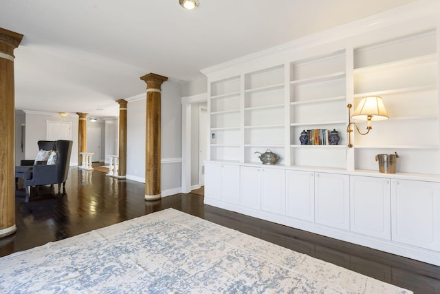 interior space featuring built in shelves, dark hardwood / wood-style flooring, crown molding, and decorative columns