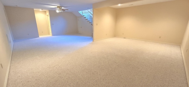 basement featuring ceiling fan and light colored carpet