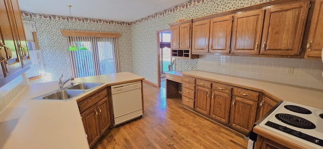 kitchen with white appliances, backsplash, sink, hanging light fixtures, and light wood-type flooring