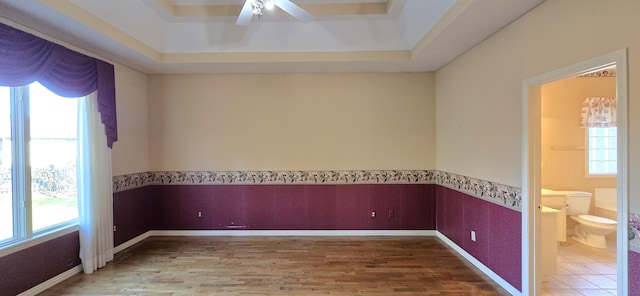 spare room with ceiling fan, wood-type flooring, and a tray ceiling