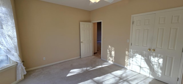 unfurnished bedroom with a closet, light colored carpet, and ceiling fan