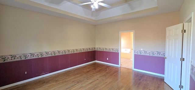 spare room with hardwood / wood-style floors, a raised ceiling, and ceiling fan