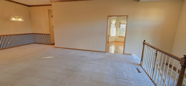 unfurnished room featuring light carpet, a chandelier, and crown molding