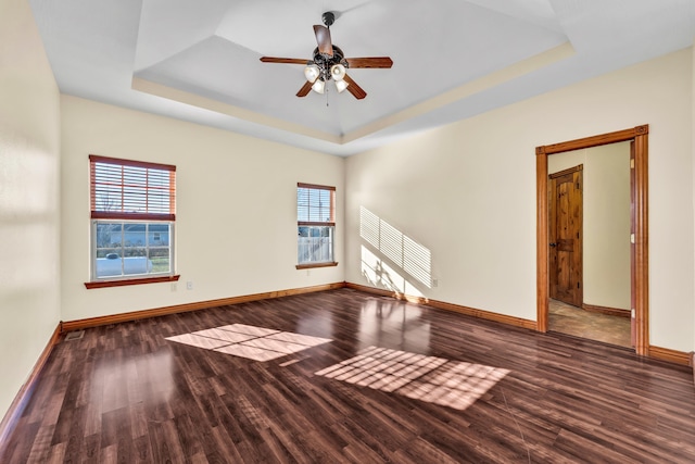 spare room featuring a raised ceiling, ceiling fan, and dark hardwood / wood-style flooring