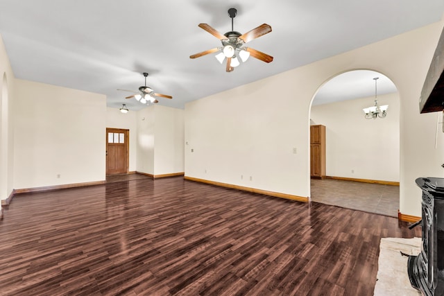 unfurnished living room featuring ceiling fan with notable chandelier and dark hardwood / wood-style floors