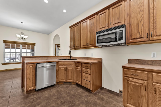 kitchen featuring appliances with stainless steel finishes, dark tile patterned floors, sink, pendant lighting, and a notable chandelier