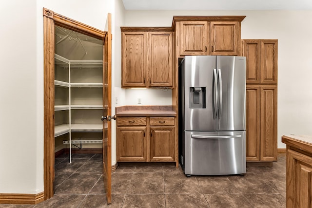 kitchen with stainless steel refrigerator with ice dispenser and dark tile patterned flooring