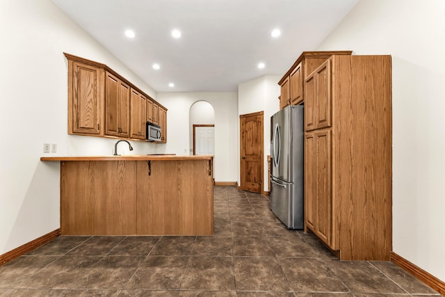 kitchen with kitchen peninsula, sink, a breakfast bar, and appliances with stainless steel finishes