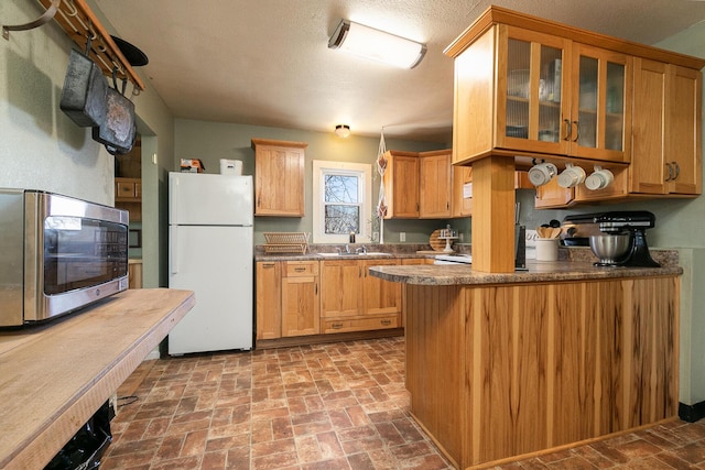 kitchen with white fridge, sink, kitchen peninsula, and a textured ceiling