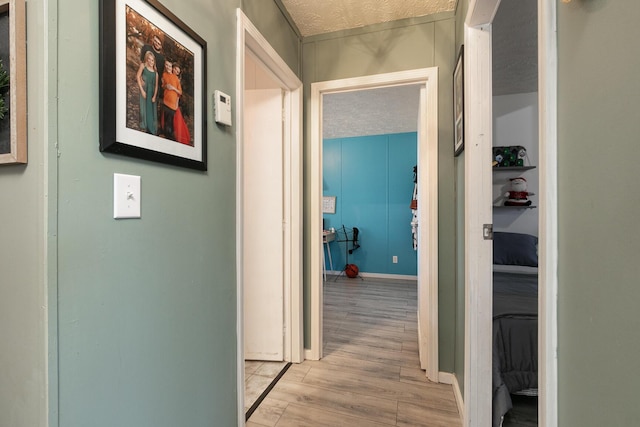 hallway with light wood-type flooring and a textured ceiling