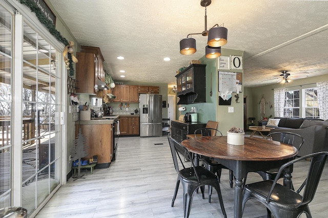 dining space with a textured ceiling, sink, light hardwood / wood-style floors, and ceiling fan with notable chandelier