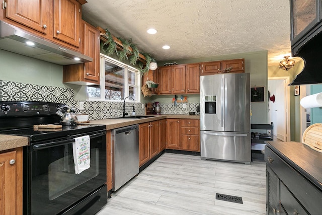 kitchen with sink, tasteful backsplash, light hardwood / wood-style flooring, a textured ceiling, and appliances with stainless steel finishes