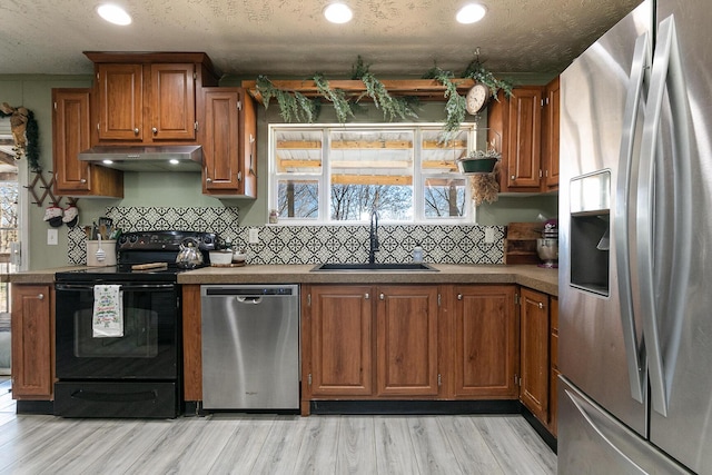 kitchen with a textured ceiling, stainless steel appliances, light hardwood / wood-style flooring, and sink