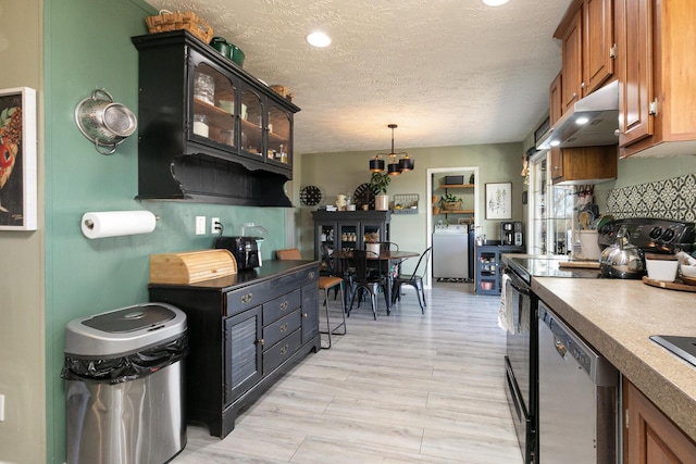 kitchen featuring a textured ceiling, appliances with stainless steel finishes, decorative light fixtures, light hardwood / wood-style floors, and washer / clothes dryer