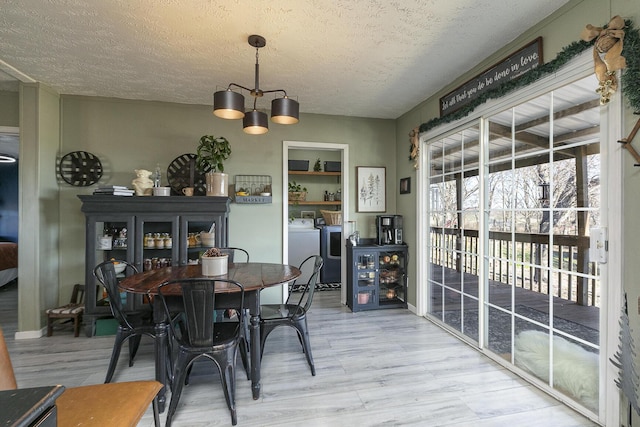 dining area featuring hardwood / wood-style flooring, a notable chandelier, washing machine and dryer, and a textured ceiling