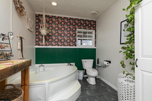 bathroom with tile patterned flooring, a washtub, toilet, and a textured ceiling