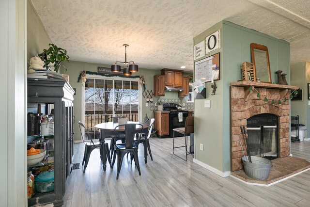 dining room featuring light hardwood / wood-style floors, a stone fireplace, and a textured ceiling