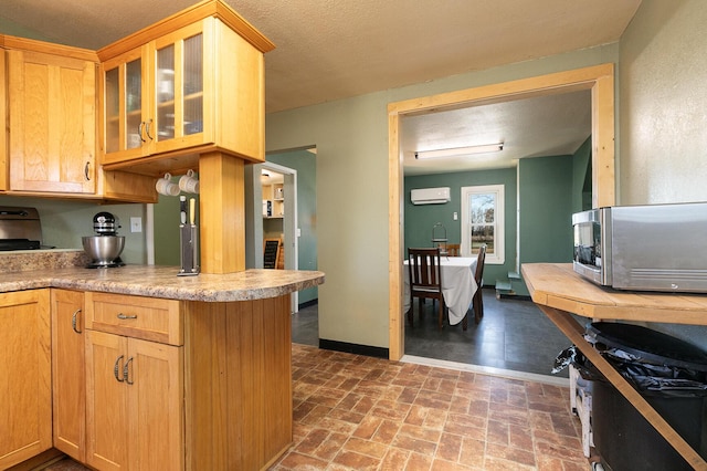 kitchen with a wall mounted air conditioner, kitchen peninsula, and a textured ceiling