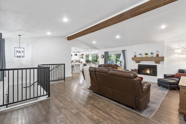 living room featuring vaulted ceiling with beams, dark hardwood / wood-style flooring, a fireplace, and a chandelier