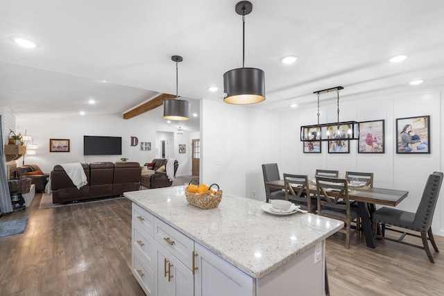 kitchen featuring white cabinetry, a center island, vaulted ceiling with beams, hardwood / wood-style floors, and pendant lighting