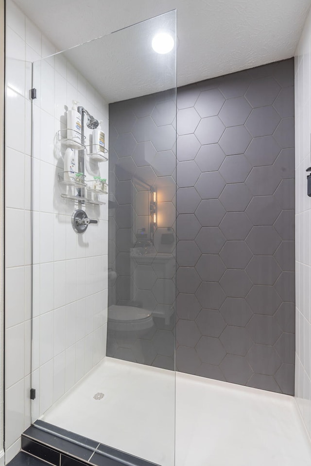 bathroom with toilet and a tile shower