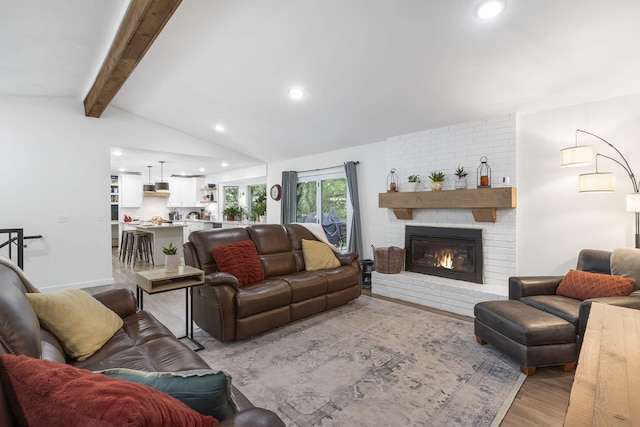 living room featuring a fireplace, lofted ceiling with beams, and light hardwood / wood-style flooring