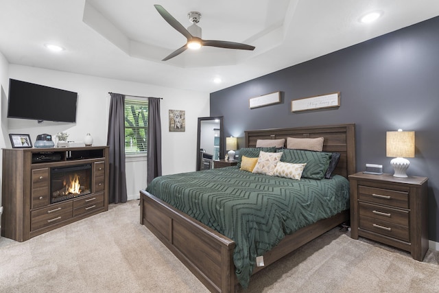 carpeted bedroom featuring a raised ceiling and ceiling fan