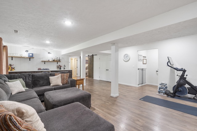 living room featuring a barn door, wood-type flooring, and a textured ceiling