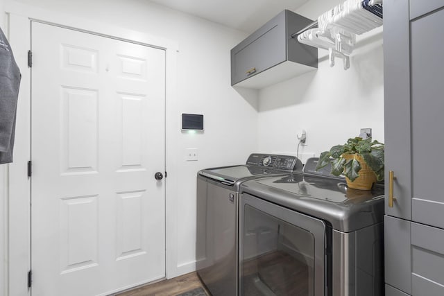 clothes washing area with washer and dryer, dark hardwood / wood-style flooring, and cabinets