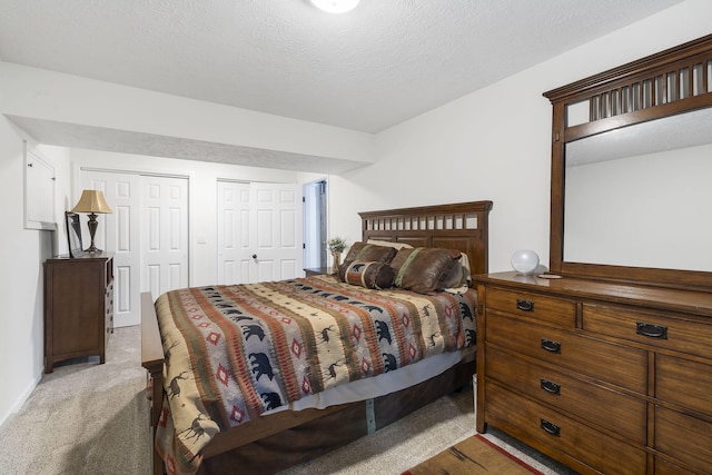 carpeted bedroom featuring a textured ceiling and two closets