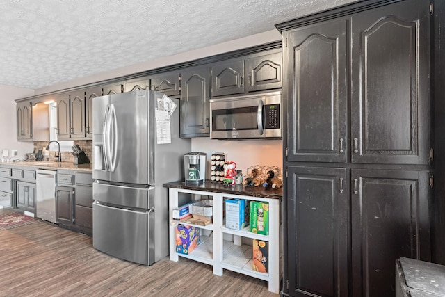 kitchen featuring a textured ceiling, sink, dark hardwood / wood-style flooring, and stainless steel appliances