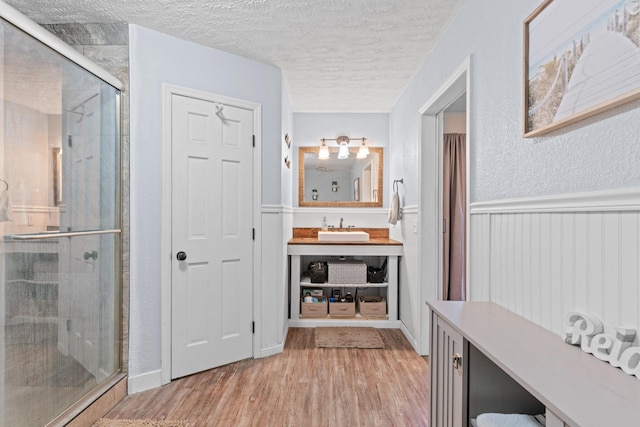 bathroom with vanity, a shower with door, wood-type flooring, and a textured ceiling